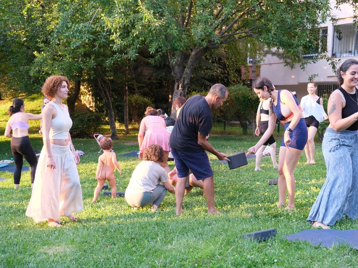 Grupo a praticar movimento com blocos de yoga ao ar livre num parque